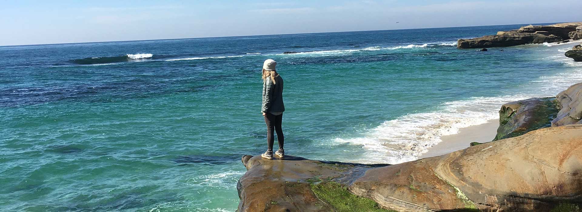 Woman on rock looking out over the ocean Woman on rock looking out over the ocean